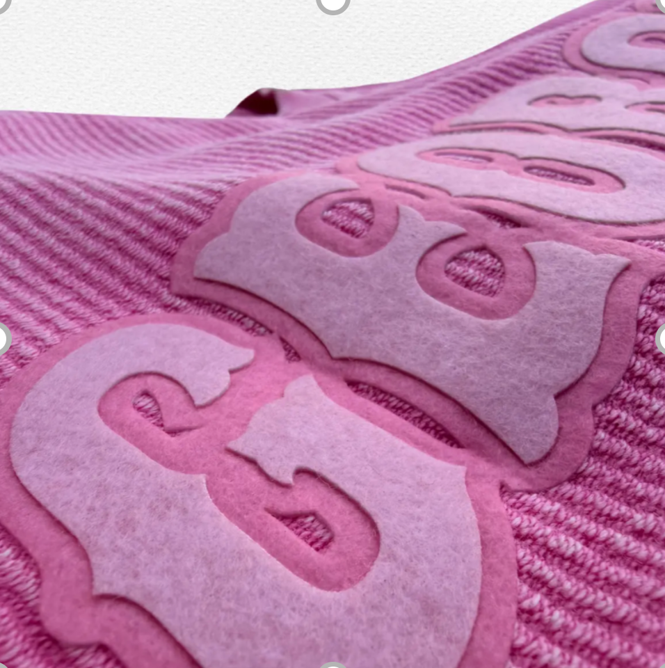 Close-up of pink Felt Edge lettering on knit fabric